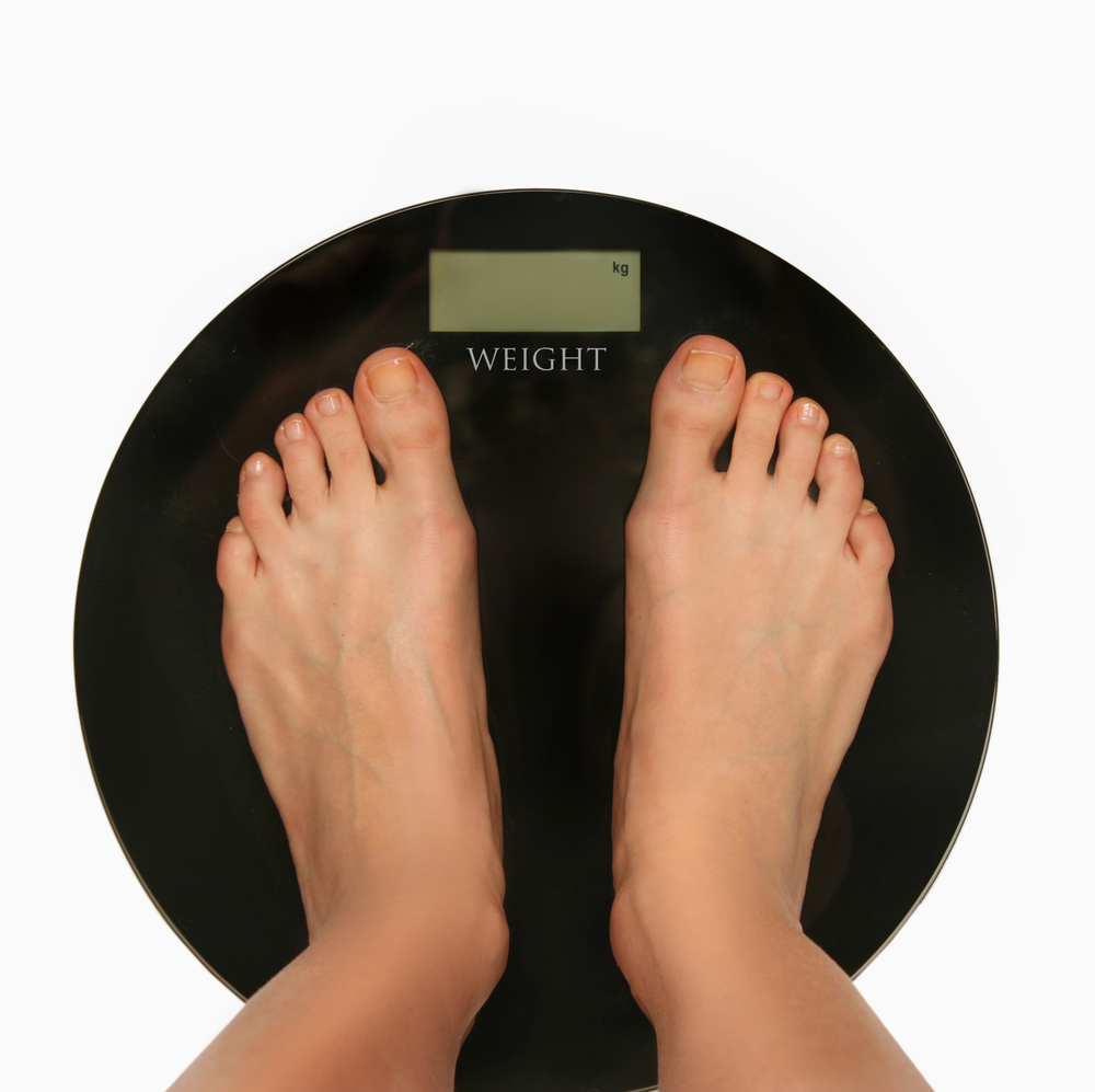 Person standing on weighing scales looking down