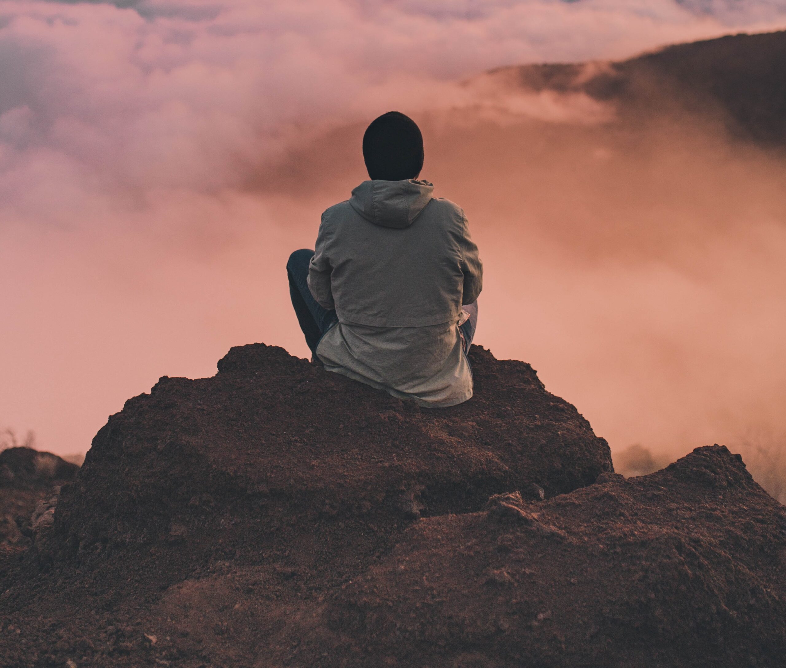 man on cliff looking mindfully out across the landscape
