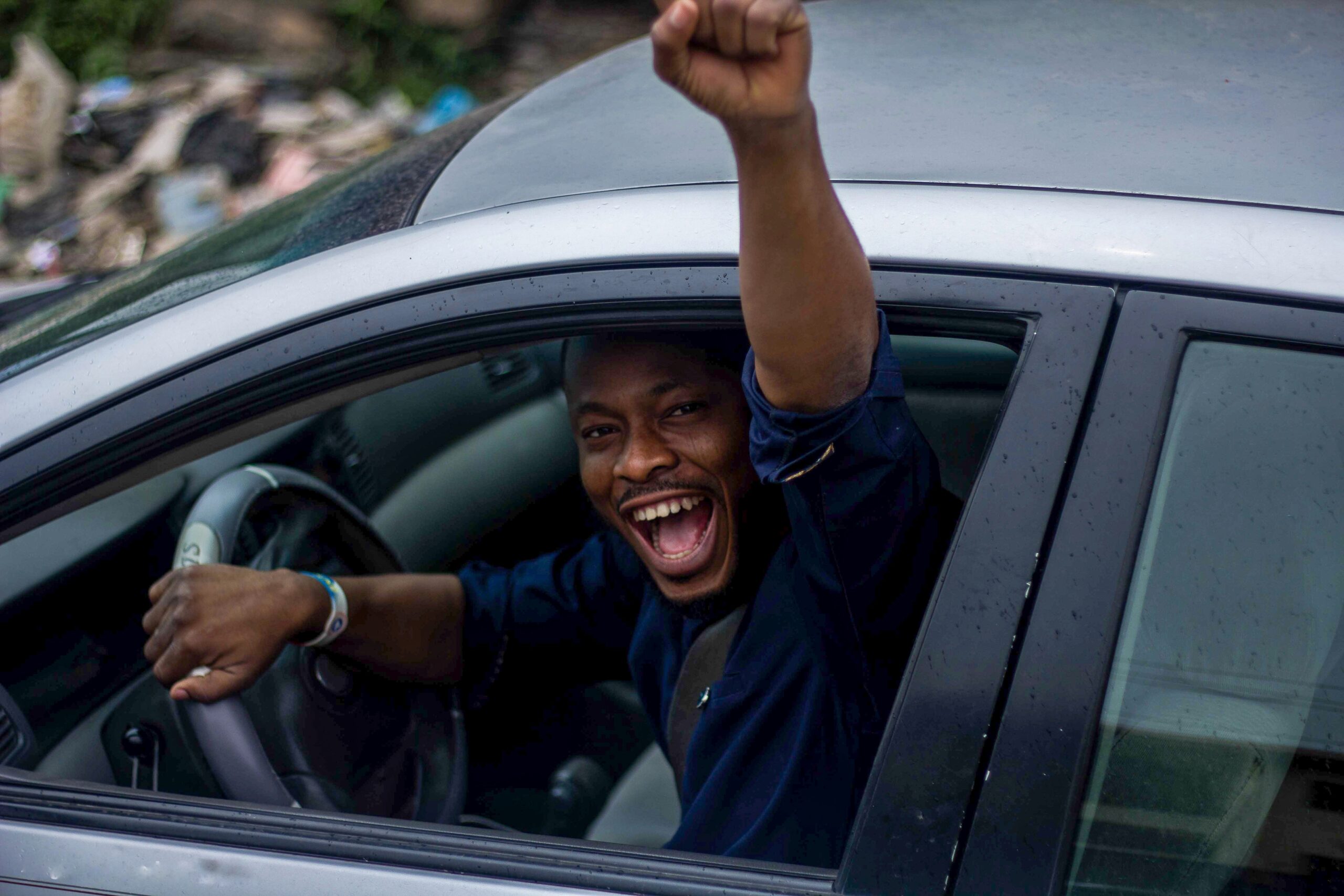 Happy man in car raising his arm in celebration